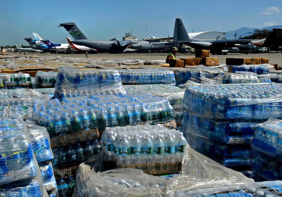 US Navy 100128-N-5345W-098 Pallets of humanitarian aid and bottled water are lined up in a staging area just off the tarmac of Aerodome de Jacmel, an airport in Port-au-Prince
