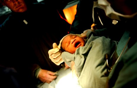 US Navy 100130-N-5345W-033 Medical personnel aboard the multi-purpose amphibious assault ship USS Bataan (LHD 5) swaddle a newborn baby after the child was born in the ship's operating photo