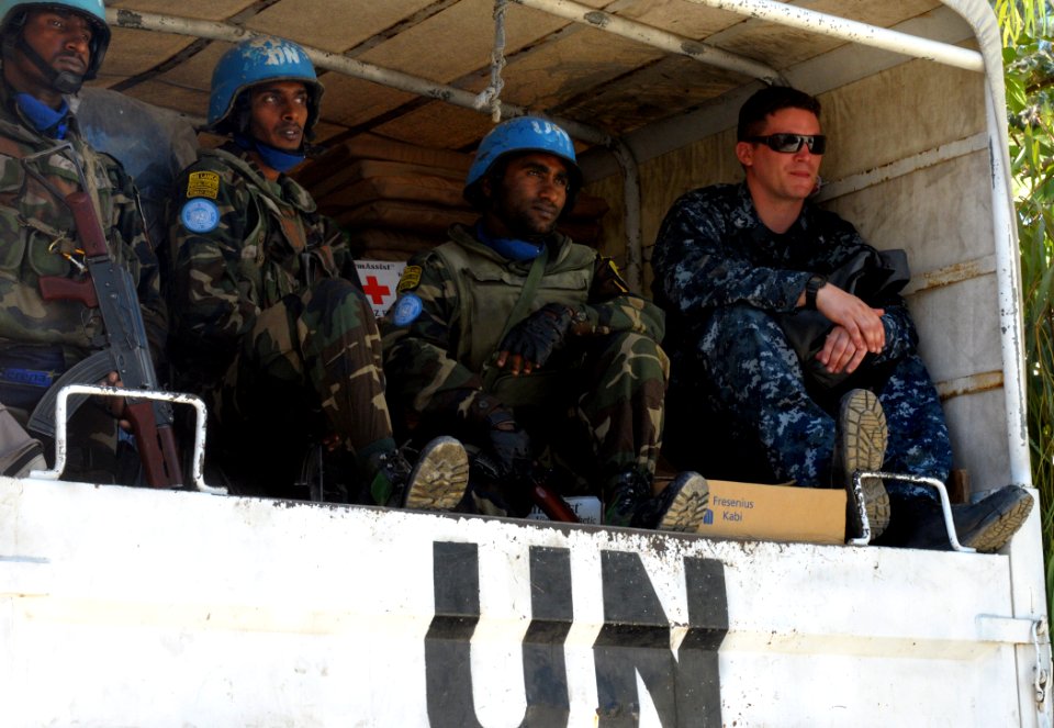 US Navy 100128-N-1831S-024 ogistics Specialist 3rd class Jerdone McGhee sits in the back of a U.N. truck with U.N. Soldiers as they prepare to drop off supplies at the Operation Hope for Children of Haiti clinic in Killick