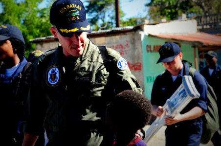 US Navy 100128-N-7508R-071 Capt. Steve Koehler, prospective commanding officer of multi-purpose amphibious assault ship USS Bataan (LHD 5) walks with a Haitian child photo