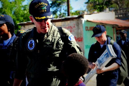 US Navy 100128-N-7508R-071 Capt. Steve Koehler, prospective commanding officer of multi-purpose amphibious assault ship USS Bataan (LHD 5) walks with a Haitian child