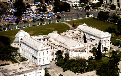 US Navy 100128-N-5345W-277 The Presidential Palace sits in ruins while hundreds of displaced Haitians take shelter in one of the many tent cities just outside the palace's main gate