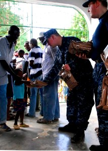 US Navy 100130-N-5244H-058 A Haitian boy receives a meal-ready-to-eat (MRE) from Sailors assigned to the dock-landing ship USS Carter Hall (LSD 50) at a Birey, Haiti school