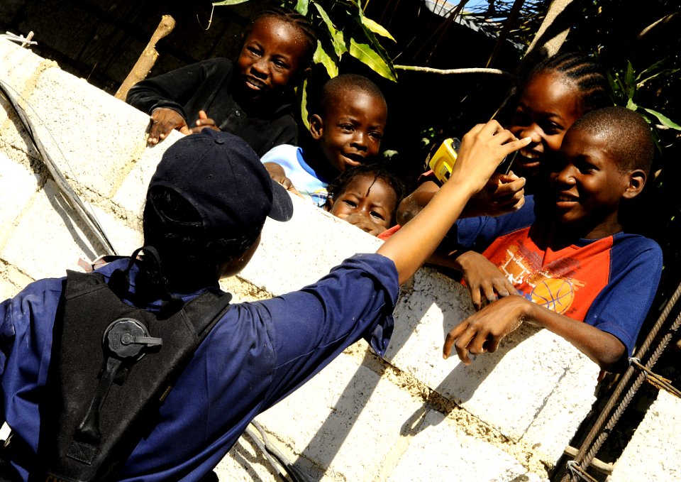 US Navy 100128-N-8655E-214 A Sailor assigned to the multi-purpose amphibious assault ship USS Bataan (LHD 5) shows Haitian children a picture of themselves at Lifeline Christian Ministry in Grand Goave, Haiti