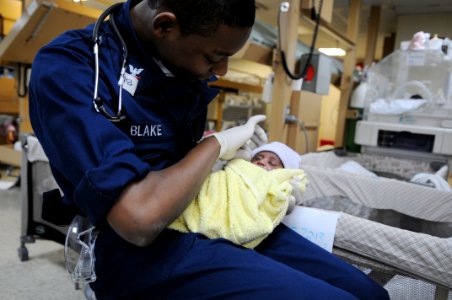 US Navy 100128-N-4995K-008 Hospital Corpsman 3rd Class Matthew Blake holds a newborn baby aboard the Military Sealift Command hospital ship USNS Comfort (T-AH 20)