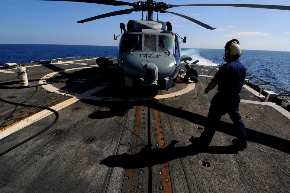 US Navy 100130-N-1688B-109 Aviation Electronics Technician 1st Class Walter Mercado oversees maintenance to helicopters on the flight deck of the guided-missile cruiser USS Hue City (CG 66)