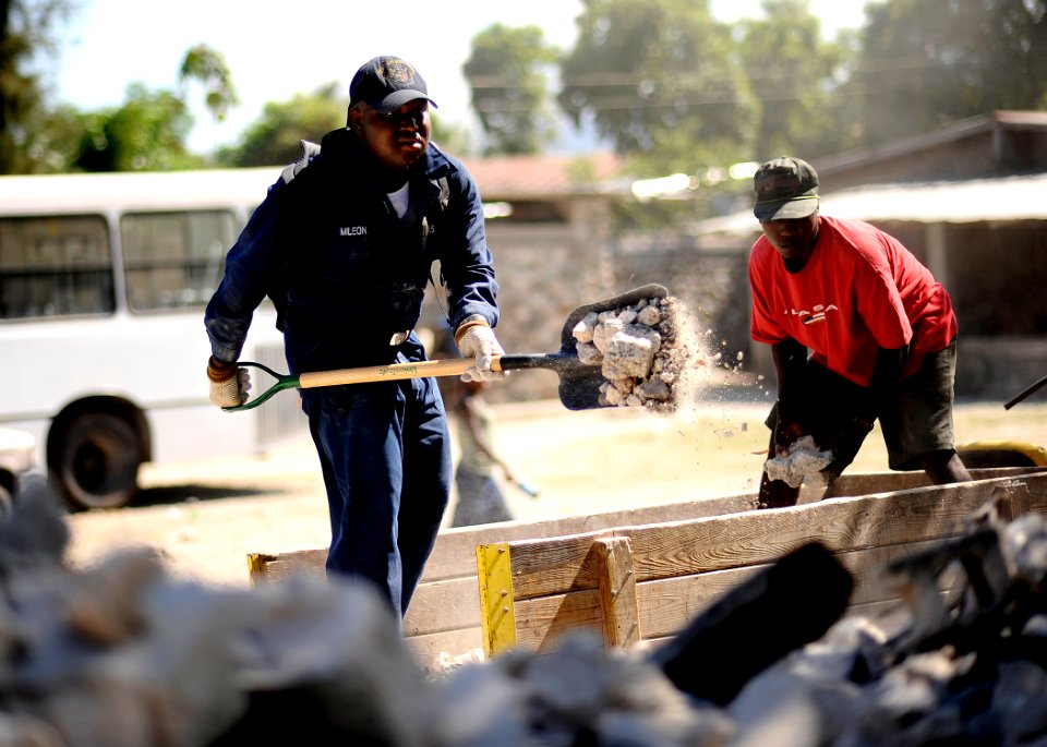 US Navy 100129-N-5345W-306 Aviation Boatswain's Mate 3rd Class Jonas Mileon helps a local Haitian citizen empty rubble from a utility vehicle