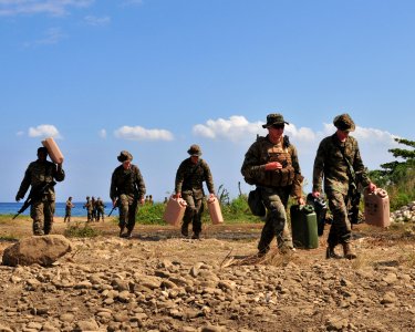 US Navy 100131-N-9740S-276 arines assigned to the 22nd Marine Expeditionary Unit (22nd MEU) embarked aboard the amphibious assault ship USS Bataan (LHD 5), carry water jugs to their camp in Grand Goave, Haiti