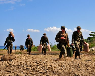 US Navy 100131-N-9740S-276 arines assigned to the 22nd Marine Expeditionary Unit (22nd MEU) embarked aboard the amphibious assault ship USS Bataan (LHD 5), carry water jugs to their camp in Grand Goave, Haiti photo