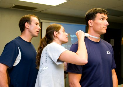 US Navy 100129-N-6674H-004 Mark McFarland, a fitness program coordinator for Navy Region Hawaii, observes Cryptologic Technician (Interpretive) 2nd Class Shannon Forbes as she performs a body composition assessment photo