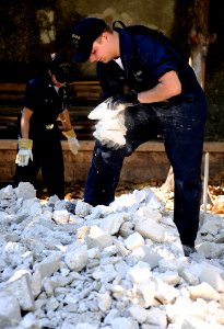 US Navy 100129-N-5345W-062 Fireman Travis Sawicki, front, and Boatswain's Mate 3rd Class Isabel Pericon remove rubble from an outdoor classroom