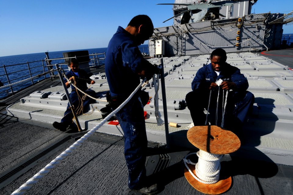 US Navy 100130-N-1688B-088 Boatswain's Mate Seaman Rutchal Mandafe, Seaman Moses Young and Boatswain's Mate Seaman Daven Arce splice a line on the missile deck of the guided-missile cruiser USS Hue City (CG 66)