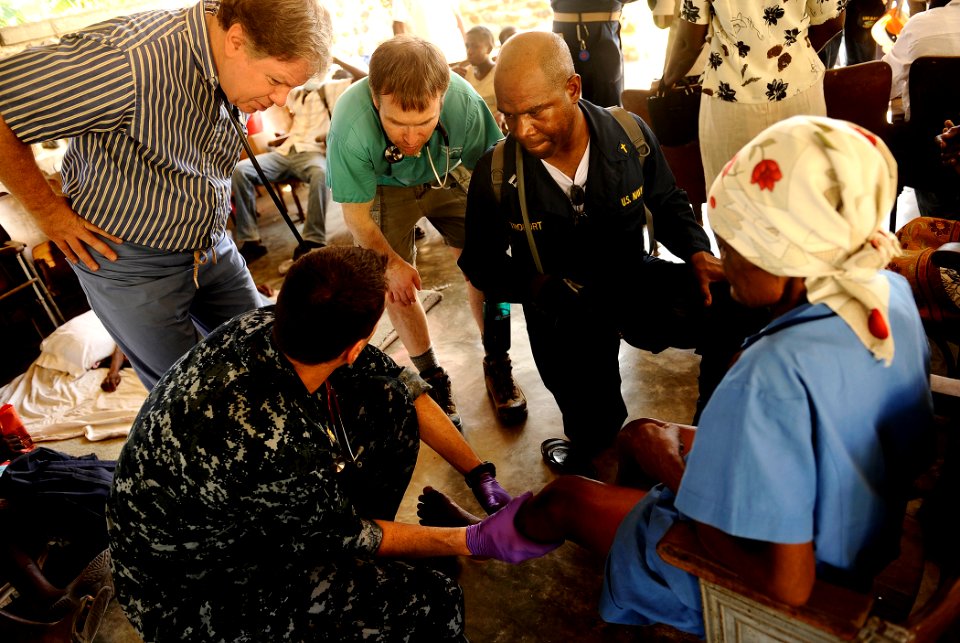 US Navy 100129-N-5345W-189 Lt. Cmdr. Jeffrey Lester, bottom left, a physician embarked aboard the multi-purpose amphibious assault ship USS Bataan (LHD 5), describes a Haitian woman's injuries to visiting members of Doctors Wit