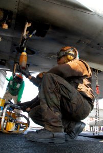 US Navy 100130-N-3327M-055 Airman Anthony Age, assigned to the Sidewinders of Strike Fighter Squadron (VFA) 86, performs preflight checks on an F-A-18C Hornet before flight operations aboard the aircraft carrier USS Nimitz (CVN