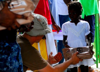 US Navy 100130-N-5244H-059 A Haitian girl receives a meal-ready-to-eat (MRE) from Sailors assigned to the dock-landing ship USS Carter Hall (LSD 50) at a Birey, Haiti school