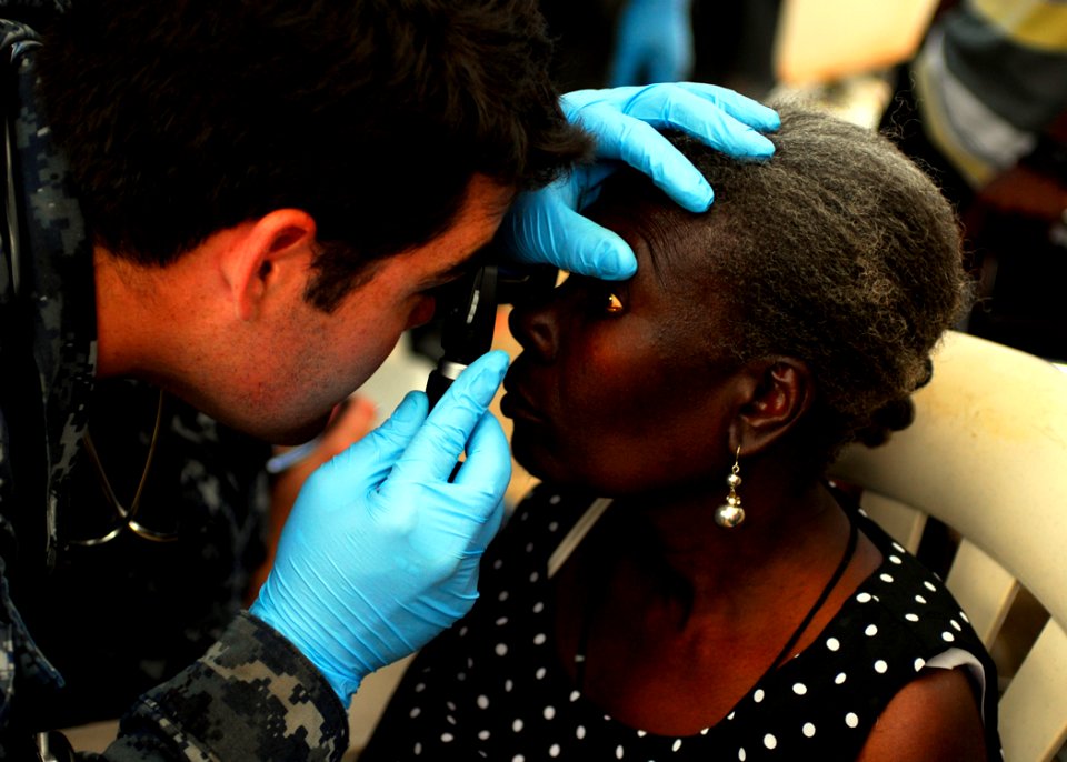 US Navy 100201-N-5244H-146 Hospital Corpsman 3rd Class Jacob Earl examines a Haitian woman's eye at a medical clinic set up by the amphibious dock-landing ship USS Carter Hall (LSD 50) medical department