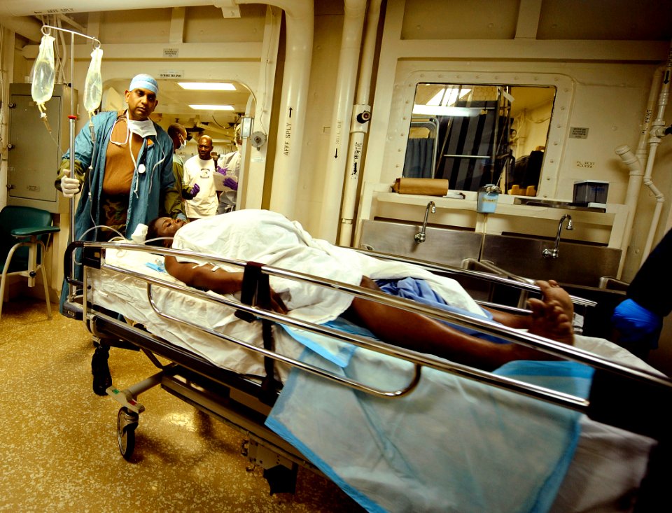 US Navy 100130-N-5345W-007 Medical personnel aboard the multi-purpose amphibious assault ship USS Bataan (LHD 5) transport a Haitian woman to an operating room