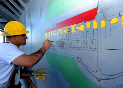 US Navy 100202-N-6676S-002 Boatswain's Mate 2nd Class Jeffrey Dixon, from Baton Rouge, La., paints a mural of Africa aboard the amphibious dock-landing ship USS Gunston Hall (LSD 44) photo