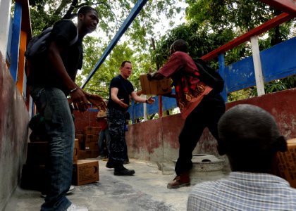 US Navy 100131-N-6676S-008 Aerographer's Mate 2nd Class Cory Clare, from Apopka, Fla. ps Haitian citizens load boxes of humanitarian aid onto the bed of a truck at the Killick Haitian Coast Guard Base photo