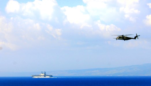 US Navy 100203-N-5214S-148 he amphibious assault ship USS Nassau (LHA 4) operates off the coast of Baie de Grand Goave, Haiti, while a CH-53E Super Stallion helicopter flies overhead photo