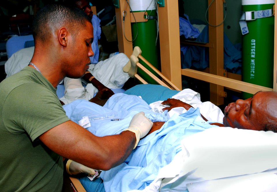 US Navy 100203-N-4047W-001 Hospitalman Christopher R. Brossard, assigned to the Military Sealift Command hospital ship USNS Comfort (T-AH 20), prepares to give a patient aboard Comfort a shot to prevent blood clotting