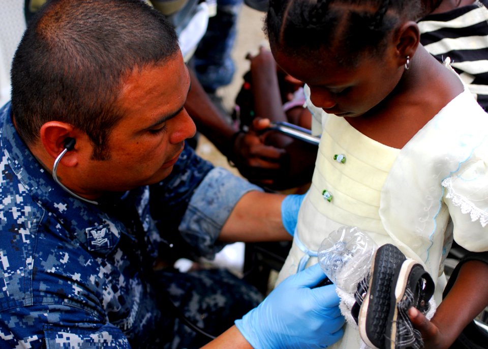 US Navy 100201-N-5244H-068 Hospital Corpsman 2nd Class Sergio Hernandez examines a Haitian girl complaining of stomach pain at a medical clinic