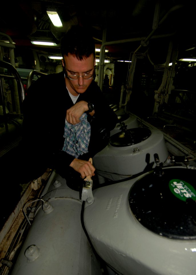 US Navy 100202-N-2000D-016 ngineman 3rd Class Joe Tips paints the main engine aboard the amphibious dock-landing ship USS Carter Hall (LSD 50)