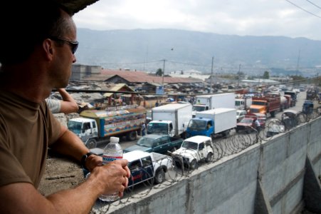 US Navy 100204-N-1134L-033 Lt. Cmdr. Tim McAllister, the mission commander of the Military Sealift Command rescue and salvage ship USNS Grasp (T-ARS 51), observes traffic flowing in and out of the main port of Port-au-Prince, H