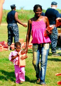US Navy 100204-N-5244H-061 Haitian woman and her daughter carry their humanitarian aid rations after receiving them at a food distribution center from Sailors assigned to the amphibious dock landing ship USS Carter Hall (LSD 5