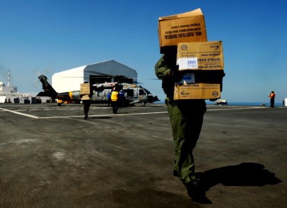 US Navy 100202-N-5345W-095 crewmen and flight deck personnel unload medical relief supplies from an MH-60S Sea Hawk helicopter