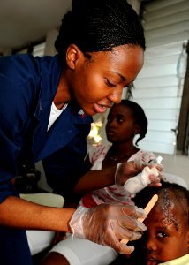 US Navy 100205-N-6676S-001 A corpsman applies an anti-bacterial ointment to the upper forehead of a Haitian child photo