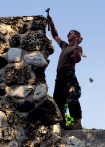 US Navy 100205-N-5244H-016 tilitiesman 3rd Class John Pruitt chips away the damage on a building at Hospital Cardinal Leger photo