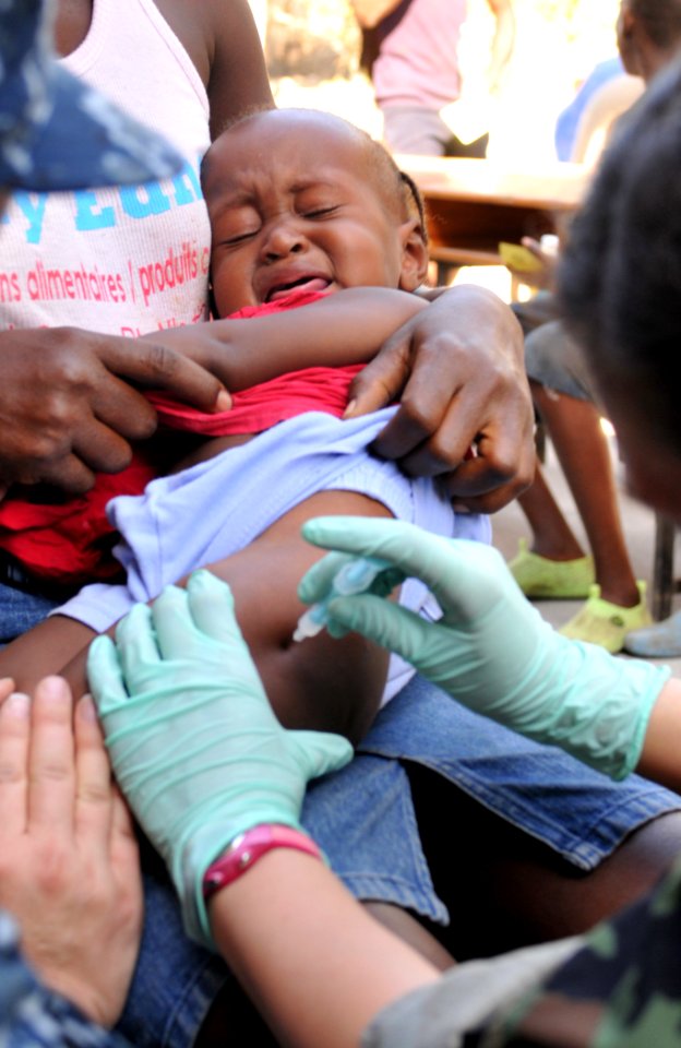 US Navy 100204-N-1831S-132 Hospital Corpsman 2nd Class Gina Martinez, a member of U.S. Public Health Service, vaccinates a Haitian child