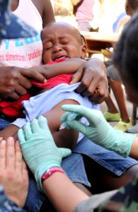 US Navy 100204-N-1831S-132 Hospital Corpsman 2nd Class Gina Martinez, a member of U.S. Public Health Service, vaccinates a Haitian child