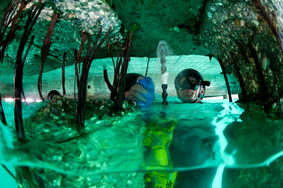 US Navy 100206-N-1134L-216 Builder 2nd Class Andrej Paskevic, assigned to Underwater Construction Team (UCT) 1, drills guide holes into a damaged section of pier at the port in Port-au-Prince