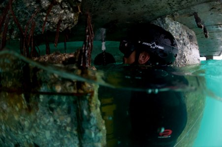 US Navy 100206-N-1134L-302 uilder 2nd Class Andrej Paskevic, assigned to Underwater Construction Team(UCT) 1, drills guide holes into a damaged section of a pier photo