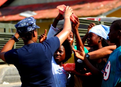 US Navy 100204-N-5244H-067 Information Systems Technician 2nd Class Judy Sylvan, assigned to the amphibious dock landing ship USS Carter Hall (LSD 50), distributes humanitarian aid rations at an aid distribution center