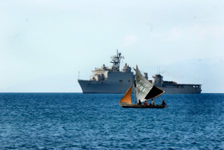 US Navy 100206-N-2000D-469 Haitian fishermen sail a sailboat as the amphibious dock landing ship USS Carter Hall (LSD 50) conducts amphibious operations off the coast of Haiti