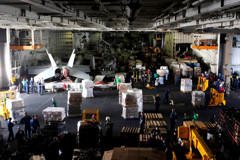 US Navy 100204-N-6604E-124 Personnel and supplies fill the hangar bay of the aircraft carrier USS Dwight D. Eisenhower (CVN 69) during an underway replenishment with fast combat support ship USNS Supply (T-AOE 6)