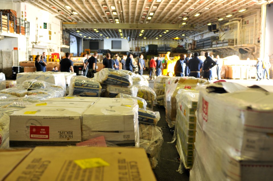 US Navy 100205-N-1831S-150 Sailors bring relief supplies into the hangar bay aboard the amphibious assault ship USS Bataan (LHD 5)