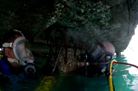 US Navy 100205-N-1134L-124 Steelworker 1st Class William Butcher, assigned to Underwater Construction Team (UCT) 1, drills guide holes into a damaged section of a pier at the port in Port-au-Prince, Haiti