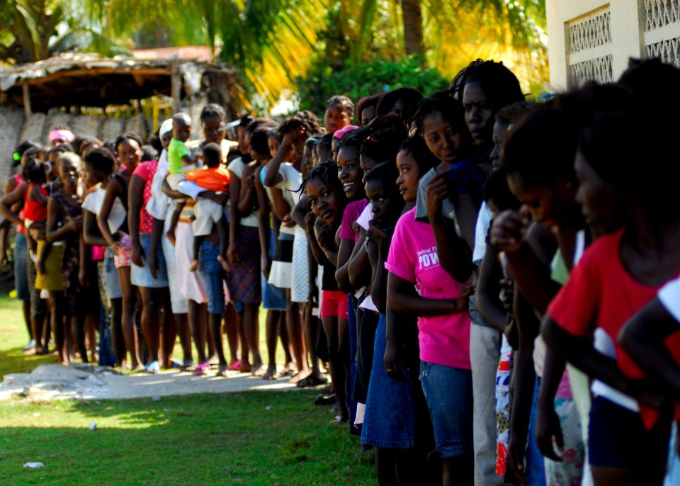 US Navy 100204-N-5244H-042 Haitian women and children queue to receive humanitarian aid rations distributed by Sailors assigned to the amphibious dock landing ship USS Carter Hall (LSD 50)