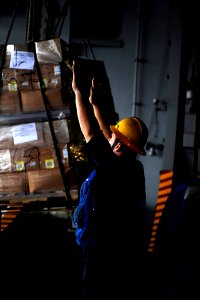 US Navy 100204-N-6604E-048 Boatswain's Mate Seaman Robert Bridgman signals to personnel from the Military Sealift Command fast combat support ship USNS Supply (T-AOE 6) during an underway replenishment