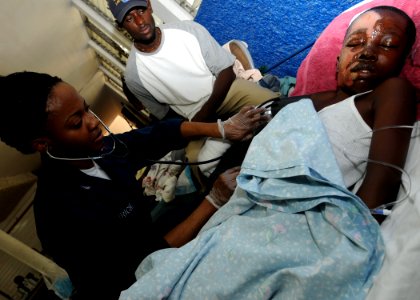 US Navy 100205-N-6676S-003 A corpsman checks the vital signs of a Haitian boy in the recovery ward at the Killick Haitian Coast Guard Base photo