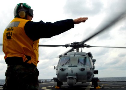 US Navy 100204-N-7058E-230 Aviation Electrician's Mate 3rd Class David Harden, assigned to Helicopter Sea Combat Squadron (HSC) 22, signals to begin a hot refueling of an MH-60S Sea Hawk helicopter