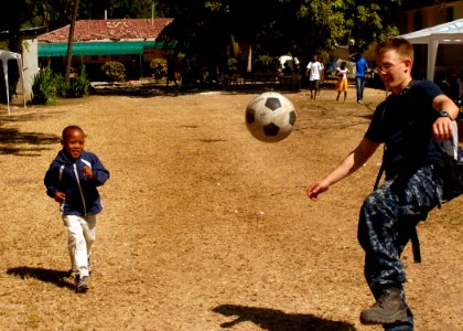 US Navy 100206-N-2000D-318 Hospital Corpsman 3rd Class Kelby Mays, from Weatherford, Texas, assigned to the amphibious dock landing ship USS Carter Hall (LSD 50), plays soccer with a boy at a field treatment camp at the Hospita