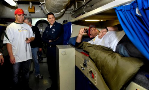 US Navy 100207-N-4954I-005 Mass Communication Specialist 1st Class Steven Owsley, middle, from Houston, shows Green Bay Packers John Kuhn, left, and Mason Crosby, right, an enlisted rack in a male berthing space