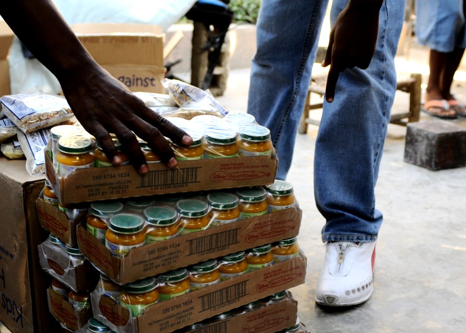US Navy 100209-N-1092P-069 A volunteer from Mouvman Fanm Aktif Kafou (MOFKA), a female-led community-support organization, distributes goods supplied by the Maritime Civil Affairs Team to Haitian families