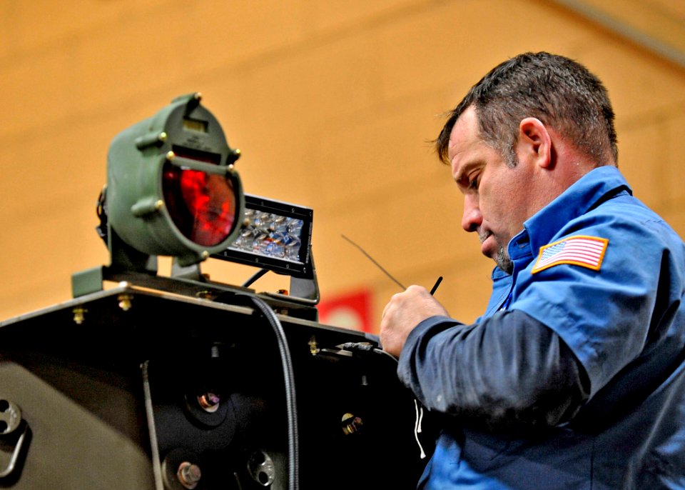 US Navy 100209-N-6889J-050 Frank Carroll, a civilian mechanic assigned to the construction equipment division of Naval Facilities Expeditionary Logistics Center, in Gulfport, Miss., installs a new LED lighting system on an up-a