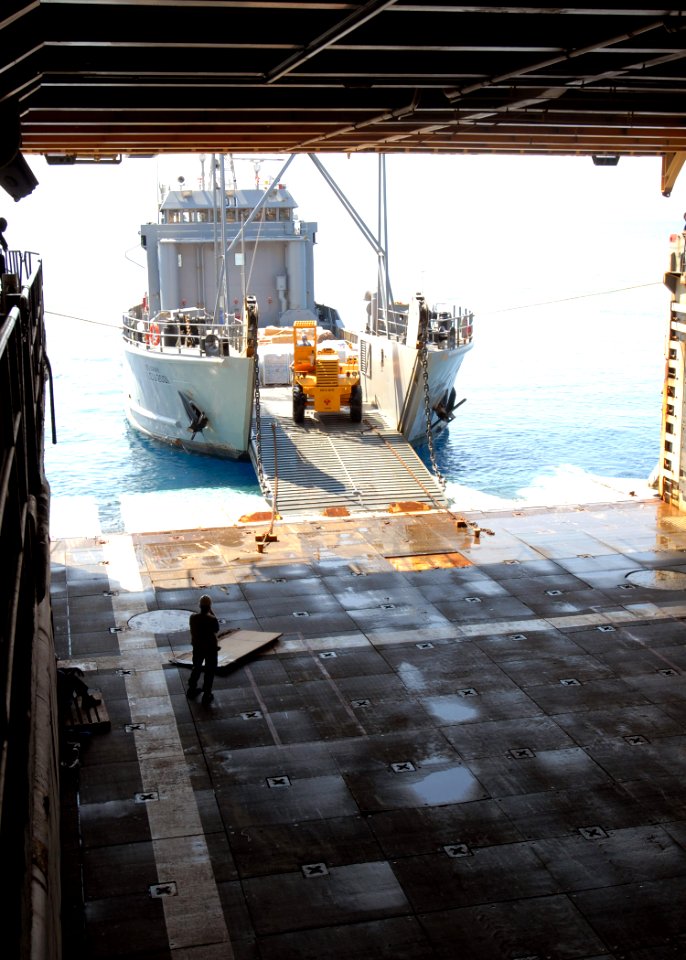 US Navy 100209-N-4971L-097 Army Landing Craft Utility (LCU) 2000 conducts a stern-gate marriage with the amphibious dock landing ship USS Fort McHenry (LSD 43) to take on pallets of relief supplies
